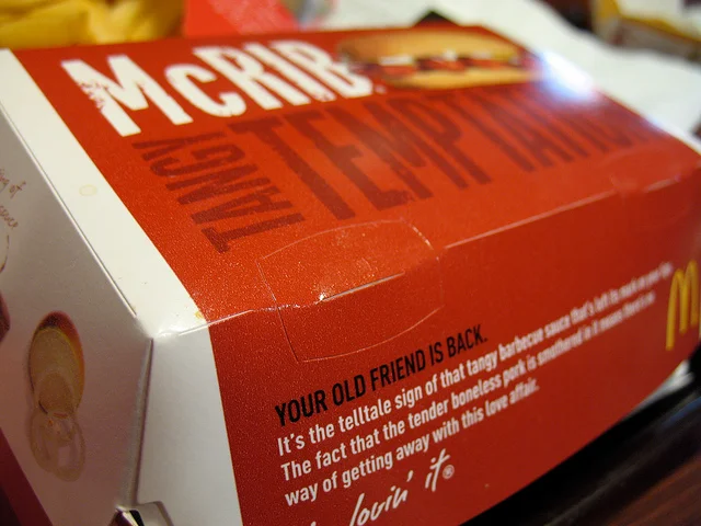 A McDonald's McRib sandwich with sauce and onions on a bun