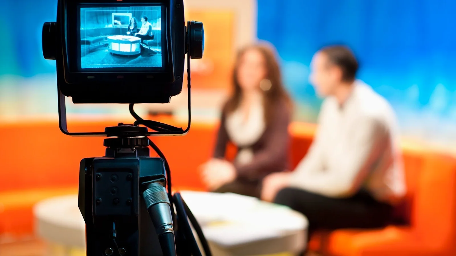 Woman smiling confidently on a television screen, offering fashion tips for broadcast appearance