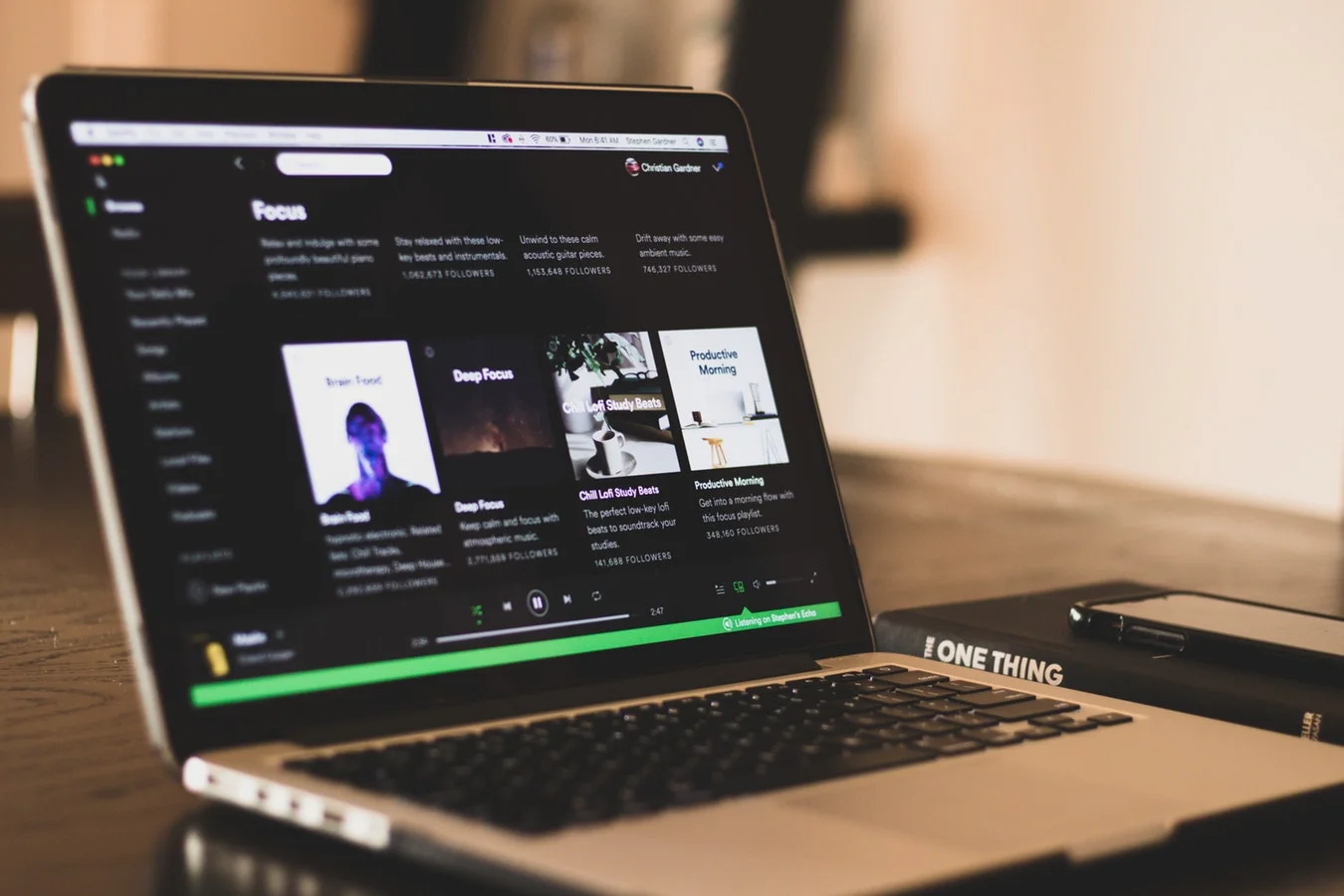 A person's hand holding a Spotify-branded phone with a user interface on screen