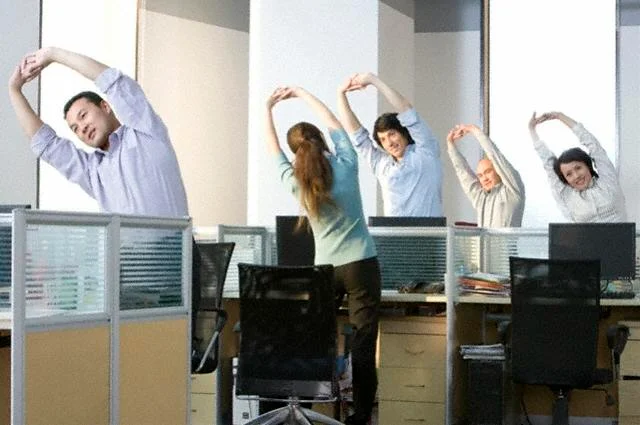 Person doing discreet stretches at an office desk while working on a laptop