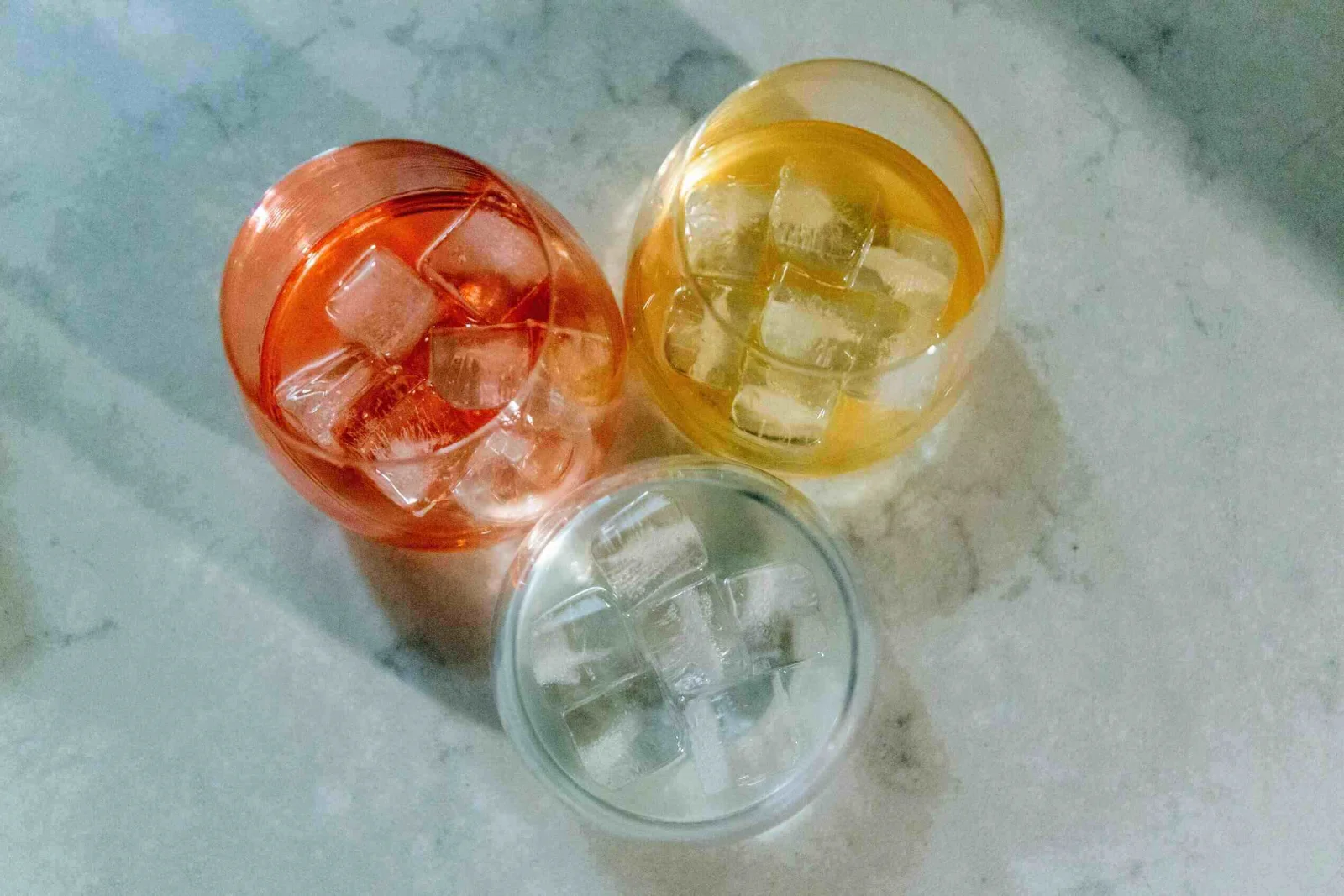Close-up of three hands holding unique, artfully presented modern beverage creations