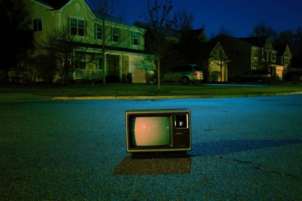 A television set outside a house at night