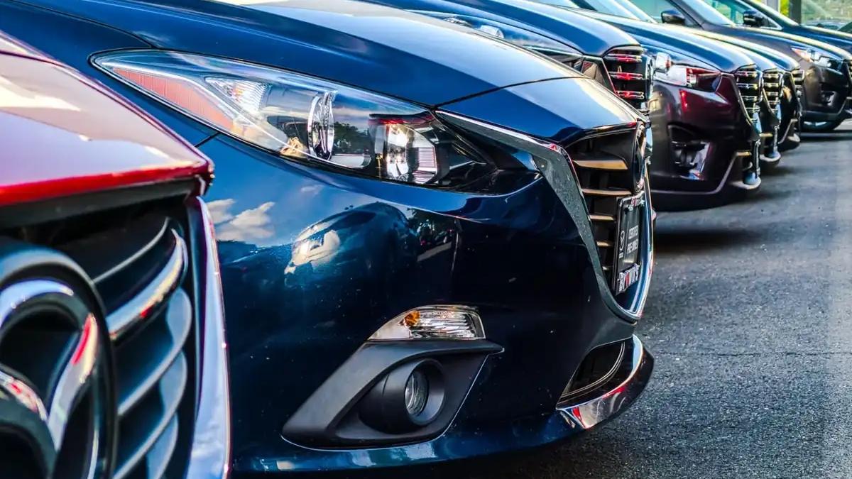 Car manufacturing plant floor with robotic arms assembling new vehicles, facing chip shortage crisis