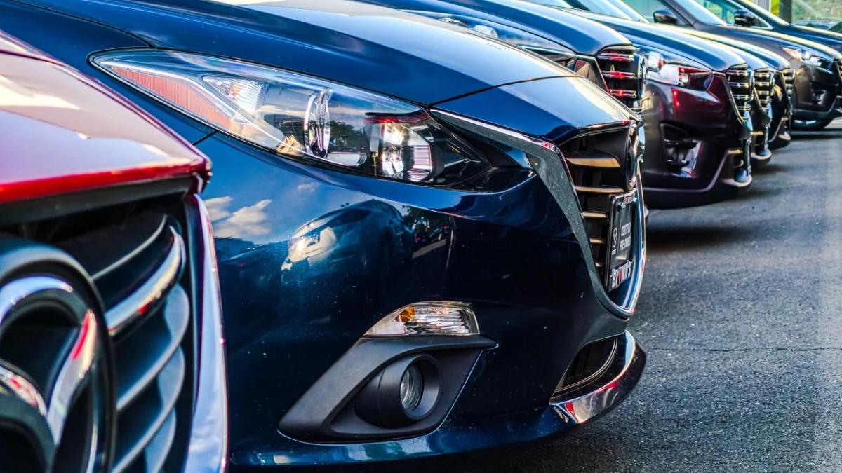 Car manufacturing plant floor with robotic arms assembling new vehicles, facing chip shortage crisis