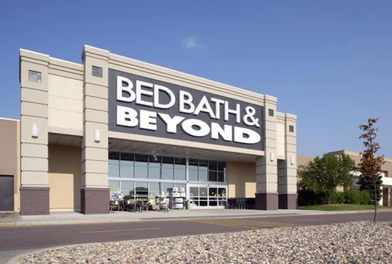 Empty shopping carts in a dimly lit Bed Bath and Beyond store aisle
