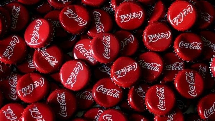 Two soda cans, one red and one blue, squared off like adversaries