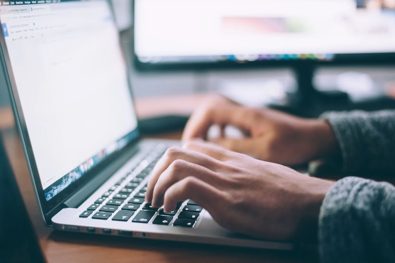 A journalist's hands typing on a laptop, illustrating modern news writing ethics