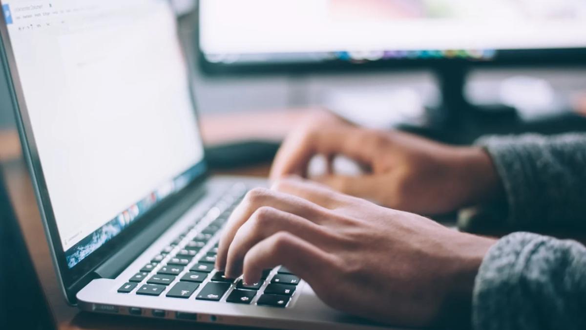 A journalist's hands typing on a laptop, illustrating modern news writing ethics