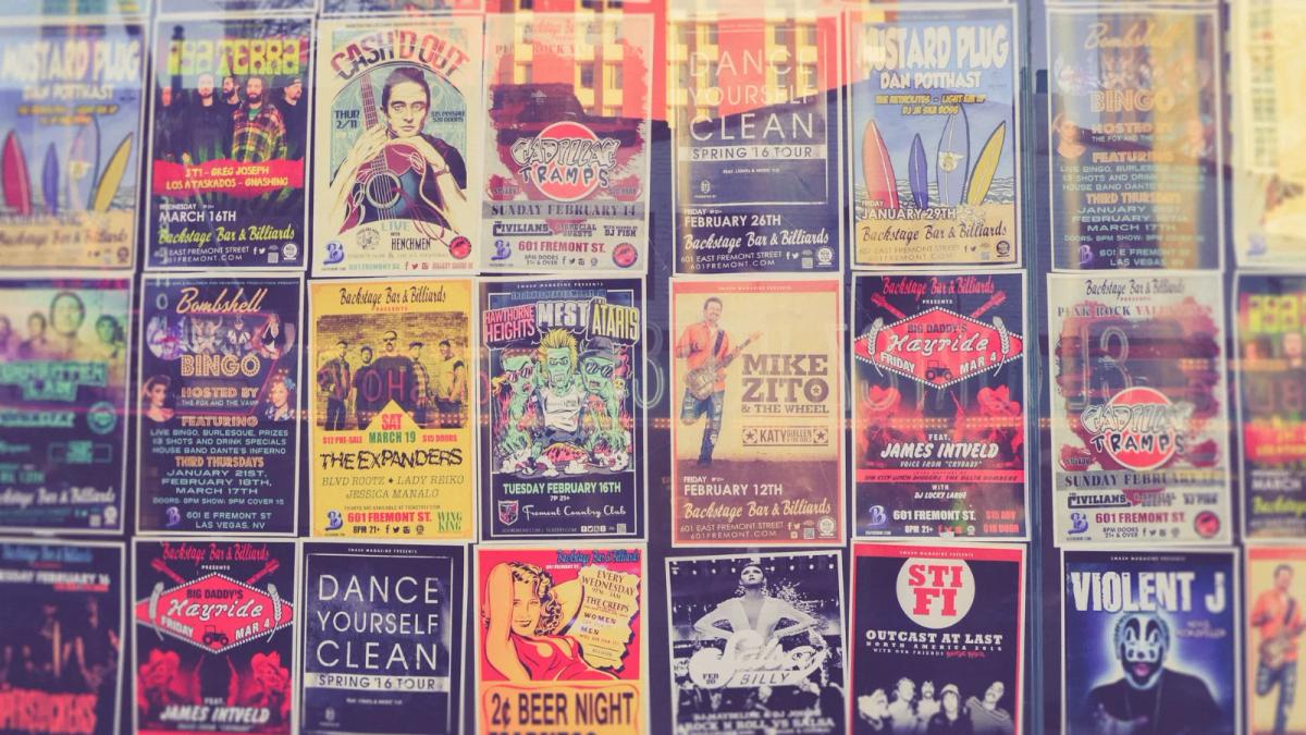 A person's hand affixing a colorful flyer to a public bulletin board