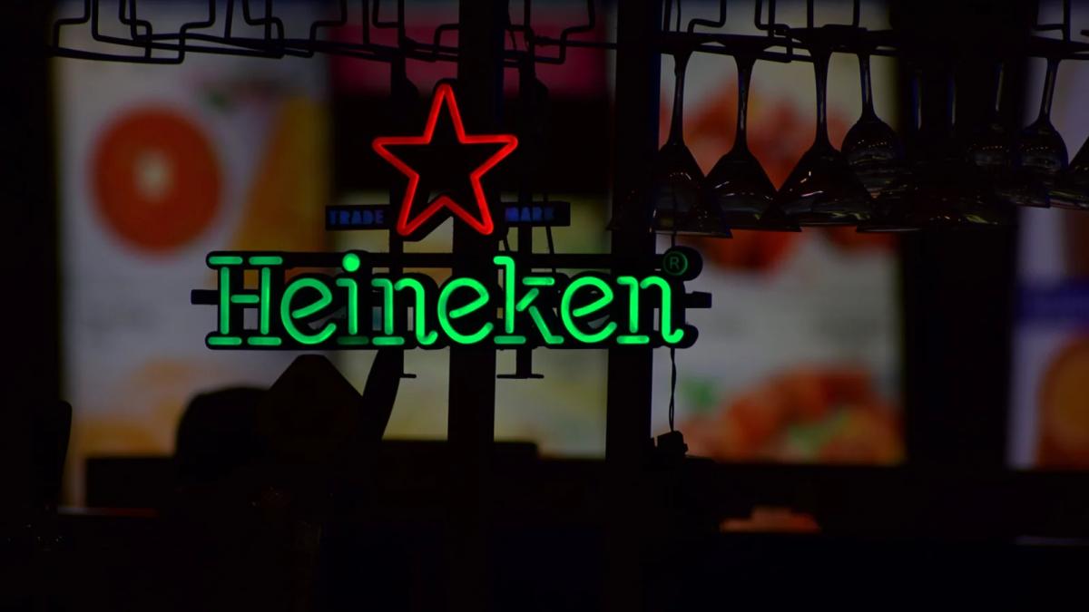 Heineken bottle opener revealing a refreshing, foamy beer in a glass