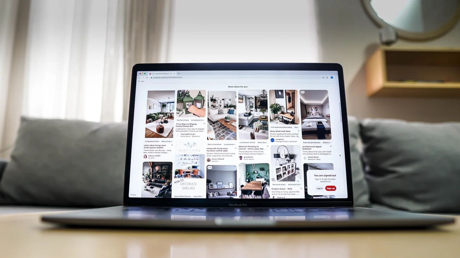 Laptop displaying Pinterest on screen with hands holding a smartphone, social media marketing