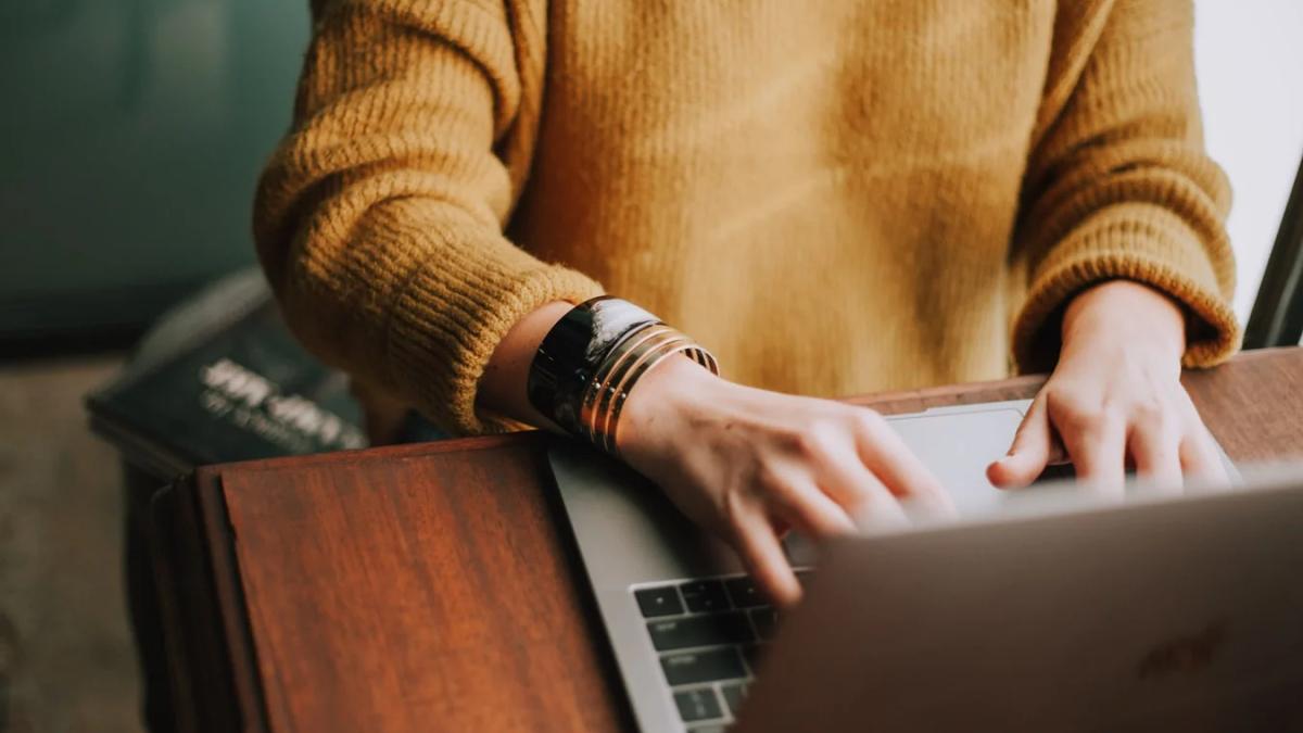 Young woman happily checking online orders on her laptop and phone