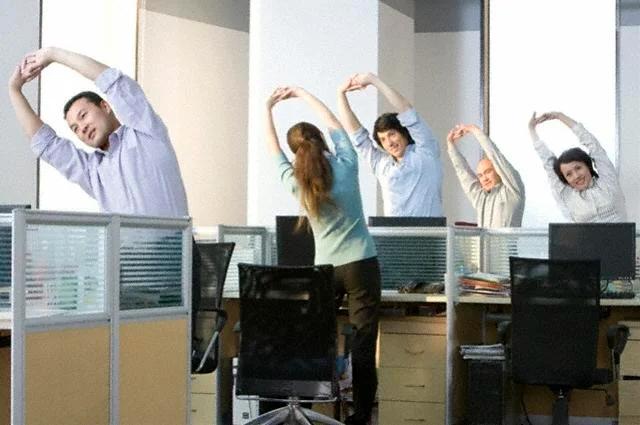 Person doing discreet stretches at an office desk while working on a laptop