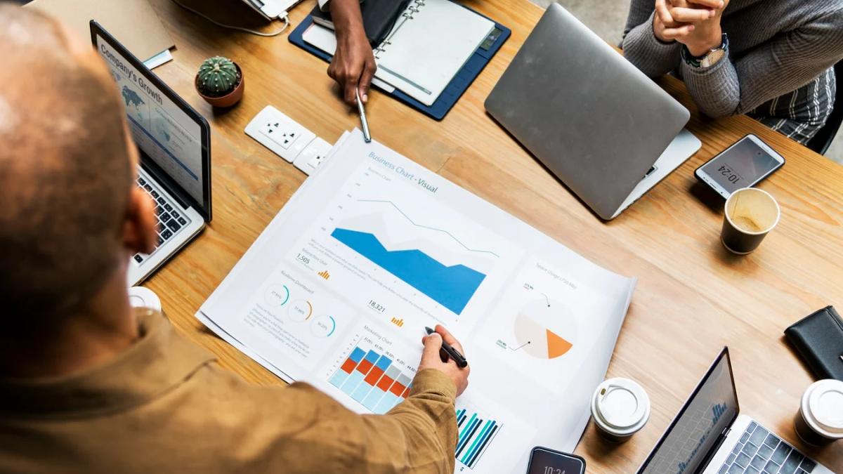 People reviewing charts and graphs while pointing to a large screen