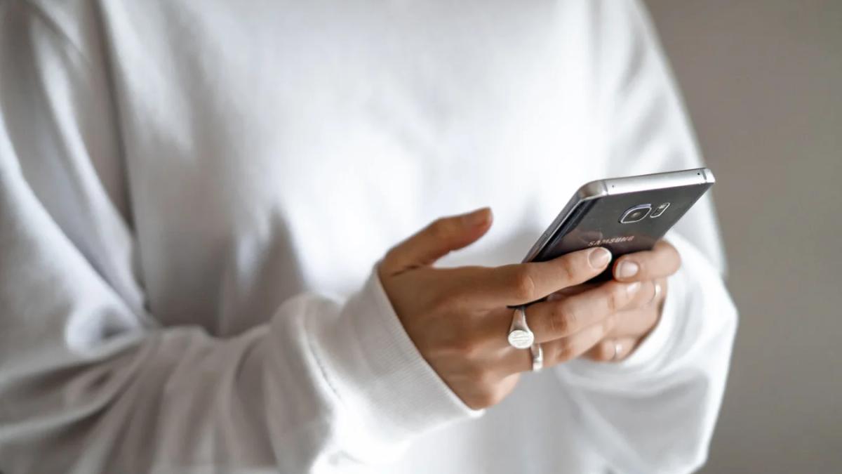 Woman's hands texting quickly on a smartphone, blurred race track in background