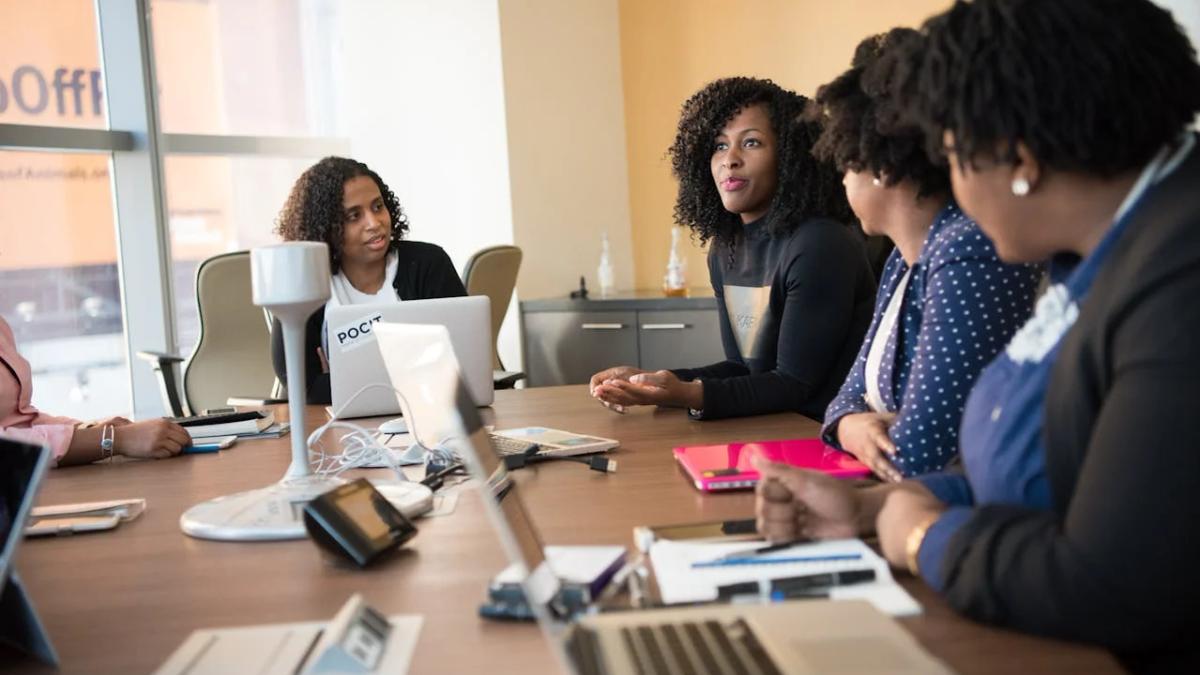 People on laptops in a bright, modern office, engaged in open communication