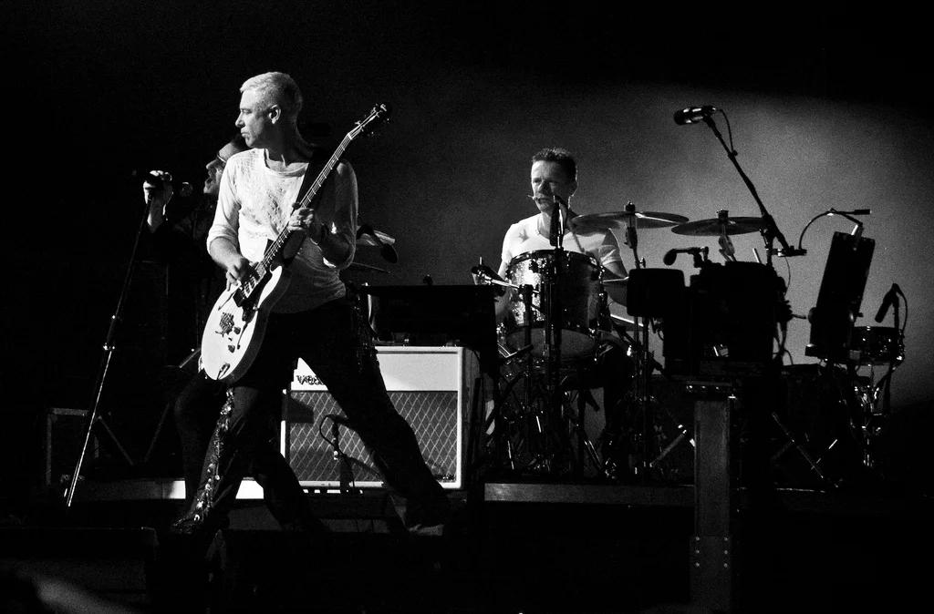 U2's Bono performing passionately on stage, captivating a massive audience with their stadium rock