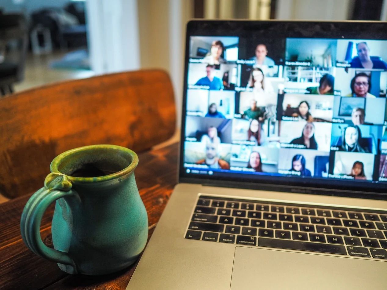 Laptop screen displaying a virtual event with diverse attendees and speaker