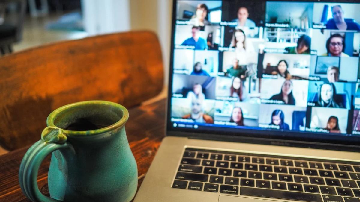 Laptop screen displaying a virtual event with diverse attendees and speaker